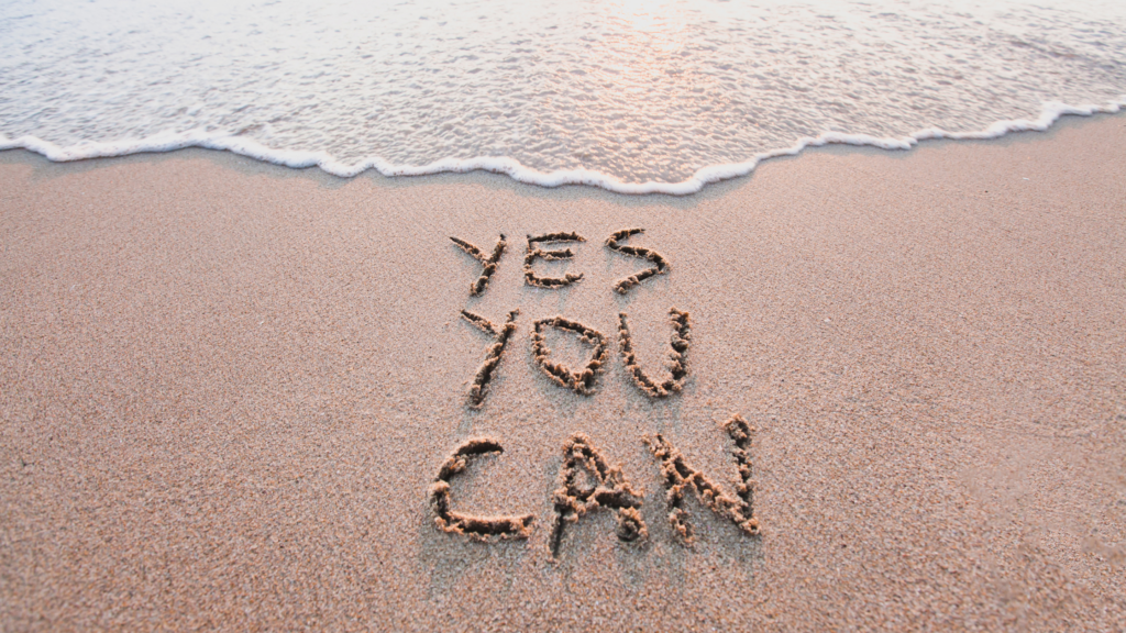 A post when the words YES YOU CAN are written on a beach